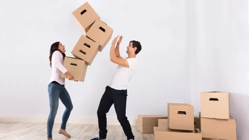 Frustrated person struggling with a stack of cardboard boxes