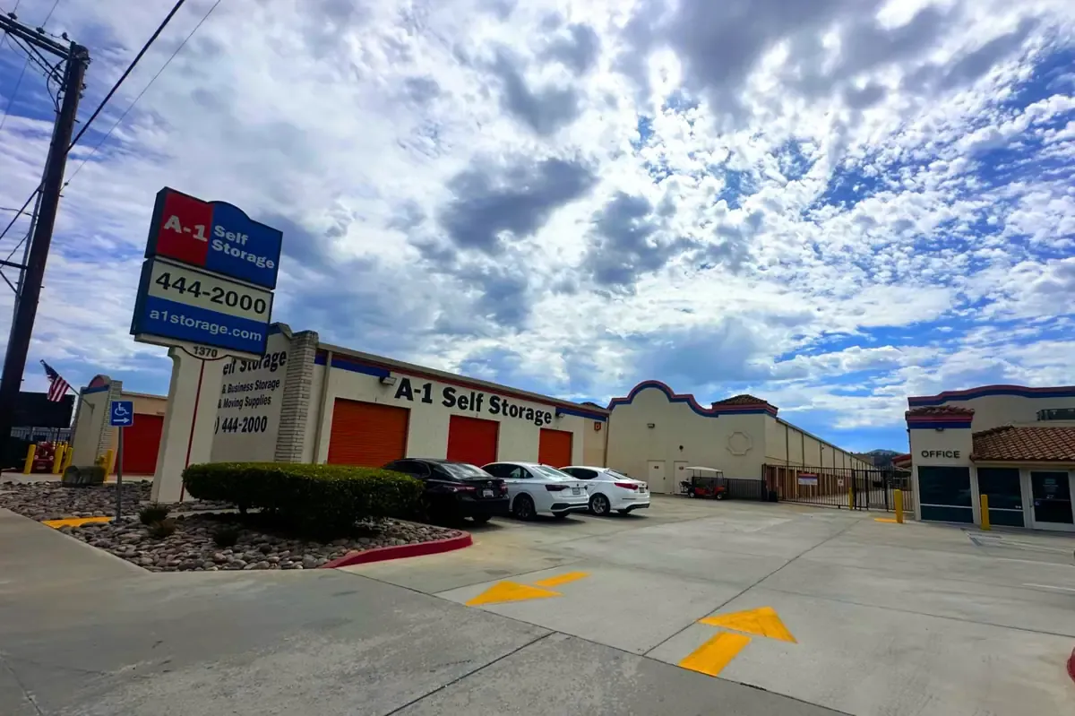 Entrance to facility, parking for visitors, and main building with drive-up units and wide driveway.